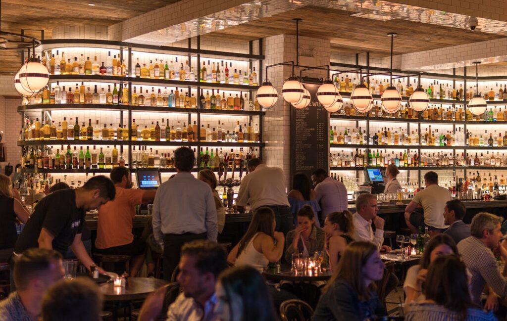 A busy restaurant with guests waiting at the bar, showing how music enhances atmosphere and customer experience.