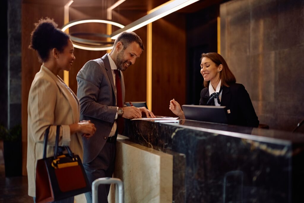 Hotel guests checking in at a front desk, illustrating how background music enhances the hospitality experience.