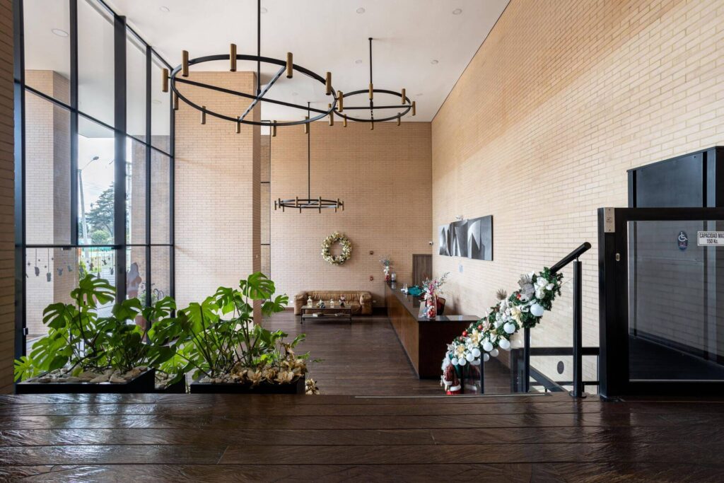Modern apartment community lobby with seating, plants, large windows, and holiday decorations.